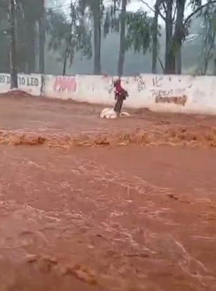 Morador em situação de rua “surfa” em avenida alagada após temporal em Campo Grande