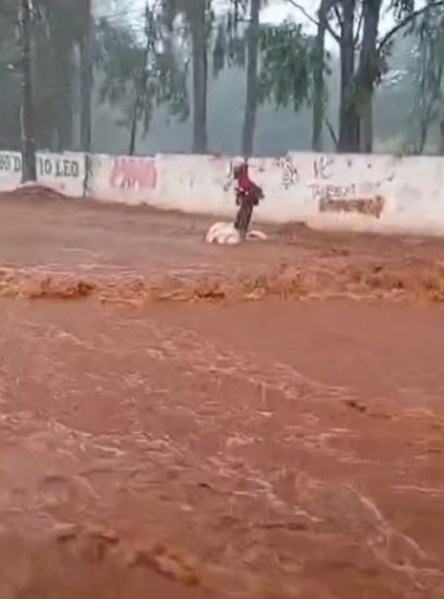 Morador em situação de rua “surfa” em avenida alagada após temporal em Campo Grande